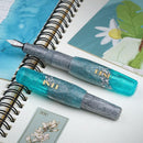 BENU Pixie Aqua Glow Fountain Pen - Two pens On Top of Notebook | EndlessPens